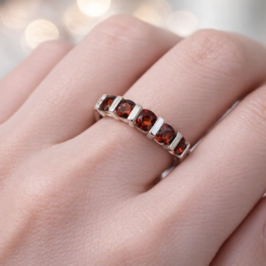 This sterling silver ring showcases five round-cut garnets, each set with precision in a smooth channel design. The deep red gemstones form a graceful line of brilliance, their rich hue symbolizing passion and timeless beauty. The channel setting offers both elegance and practicality, ensuring the stones are secure while maintaining a sleek, comfortable fit. Perfect as an anniversary band, a meaningful gift, or a distinguished addition to a jewelry collection, this five-stone garnet ring reflects craftsmanship and understated sophistication.