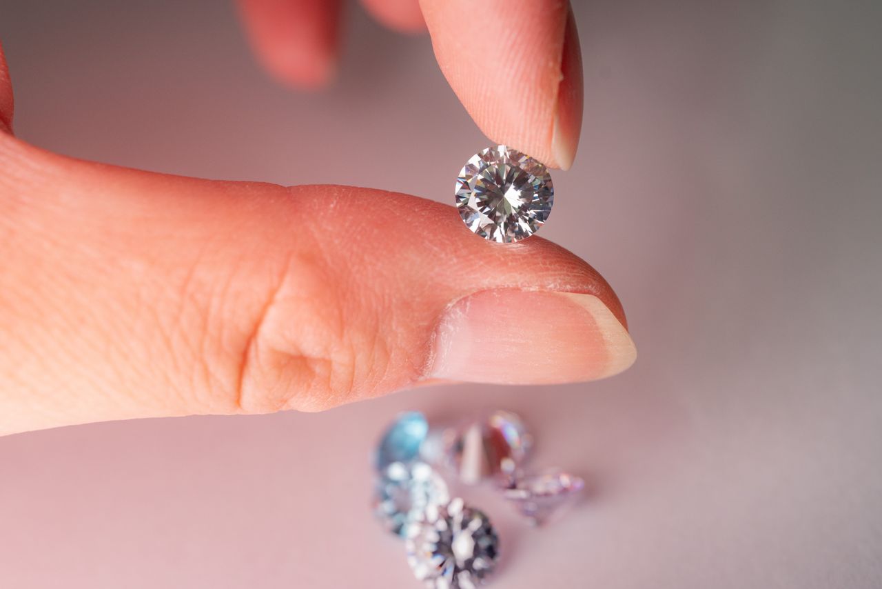 Close-up of a faceted colourless gemstone held between fingertips