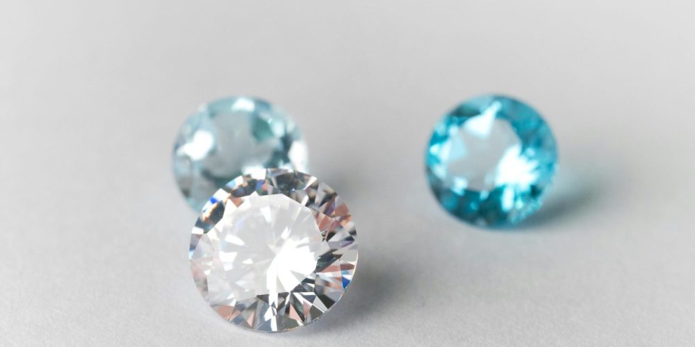 Close-up of sparkling blue and white gemstones on a smooth white surface, showcasing brilliance.